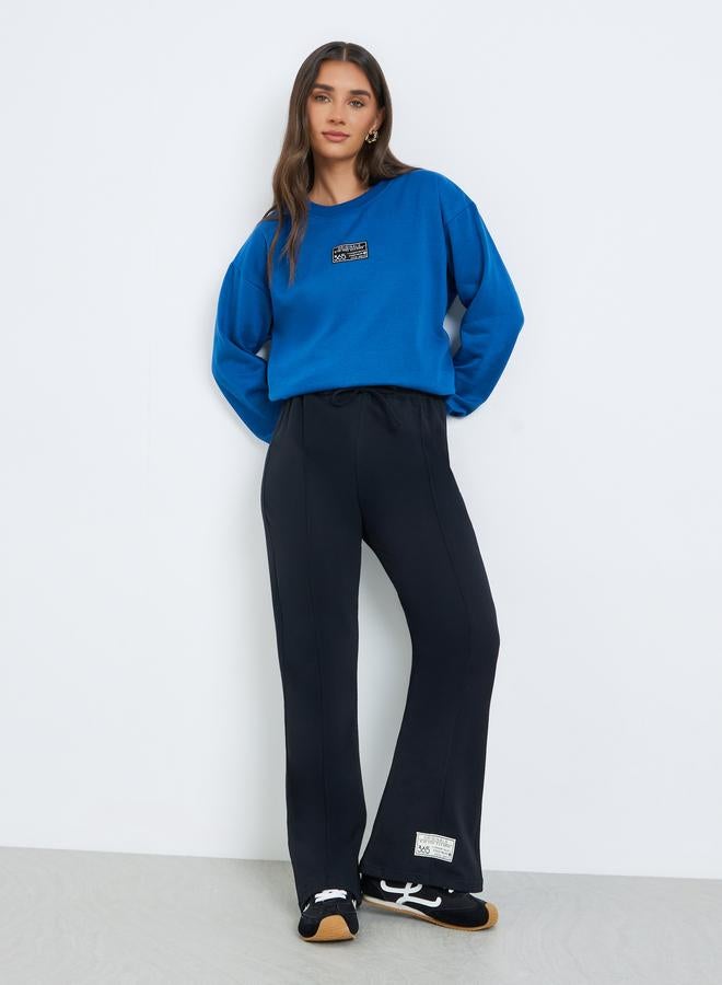 Styli Women Black  Black Wide Leg Joggers with Badge Detail - Image 1